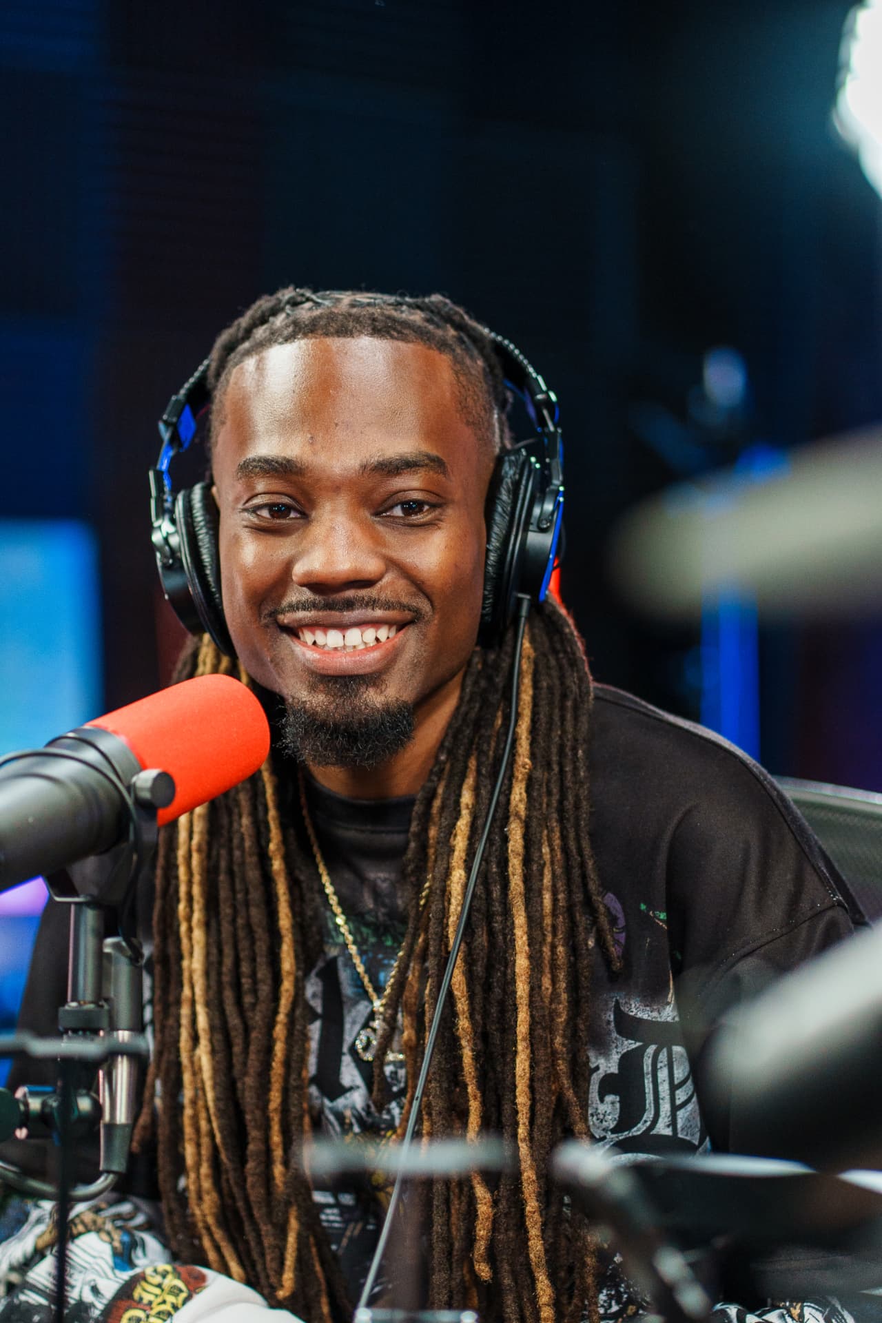Man with headphones smiling behind a podcast microphone