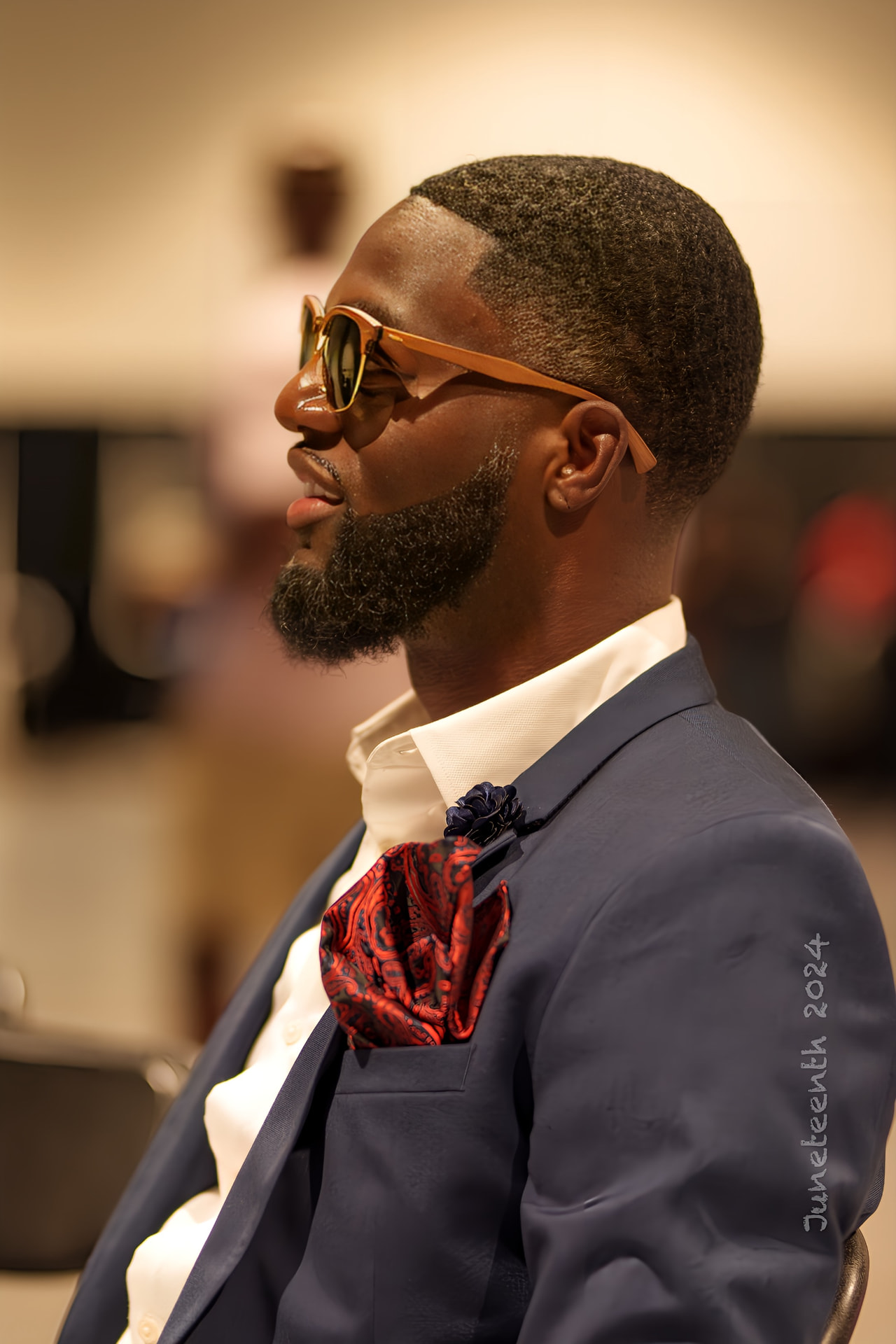 Man in a navy suit and sunglasses photographed in profile