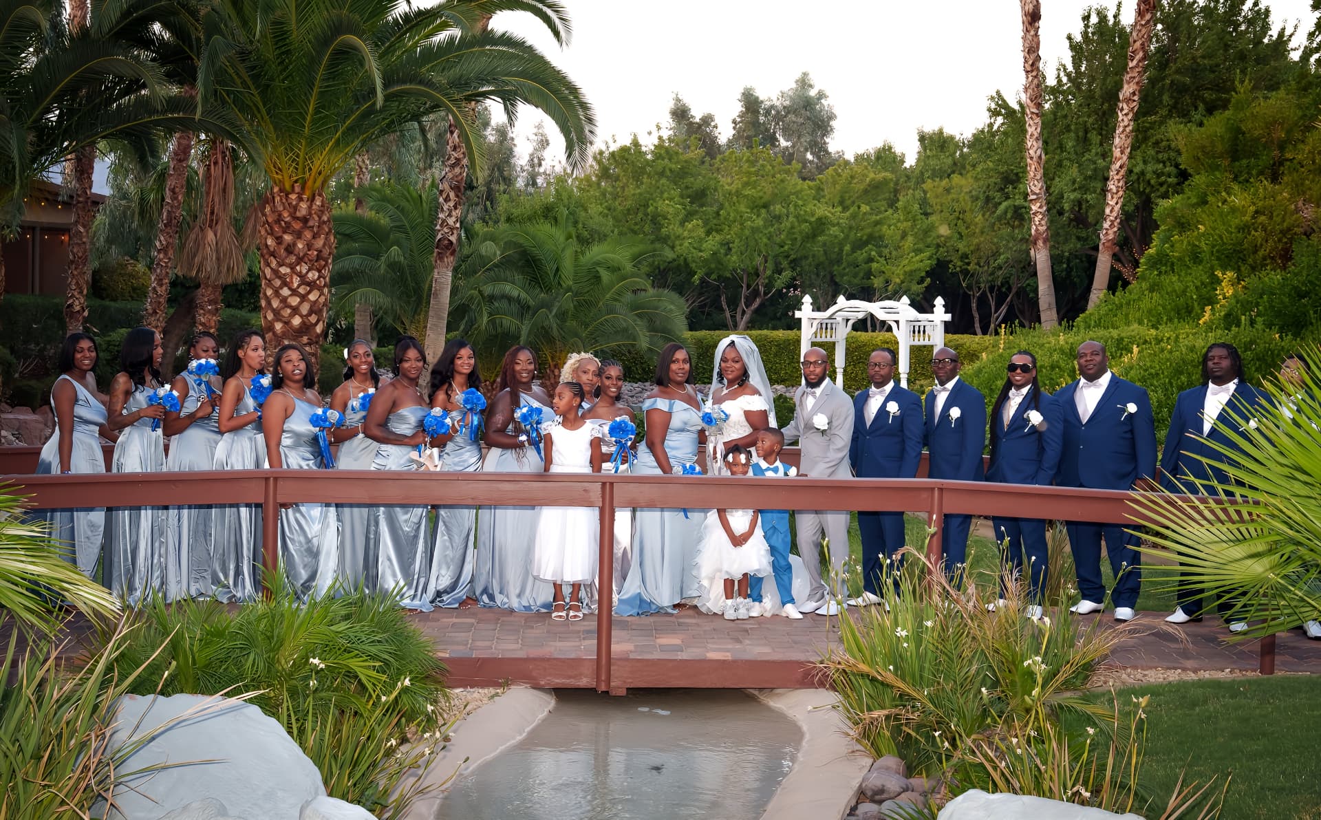 Wedding party posing together on a garden bridge