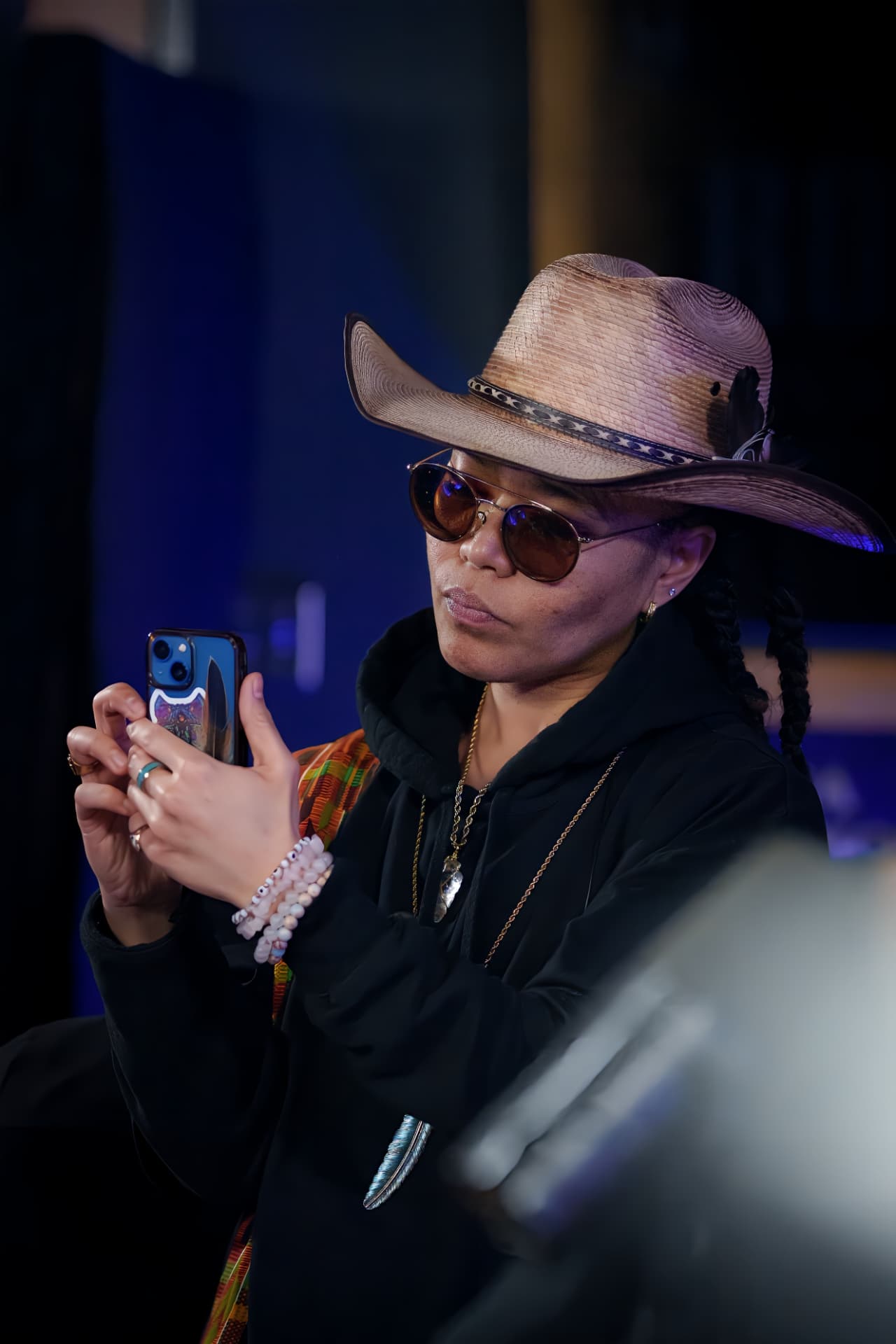 Woman in a cowboy hat and sunglasses looking at her phone